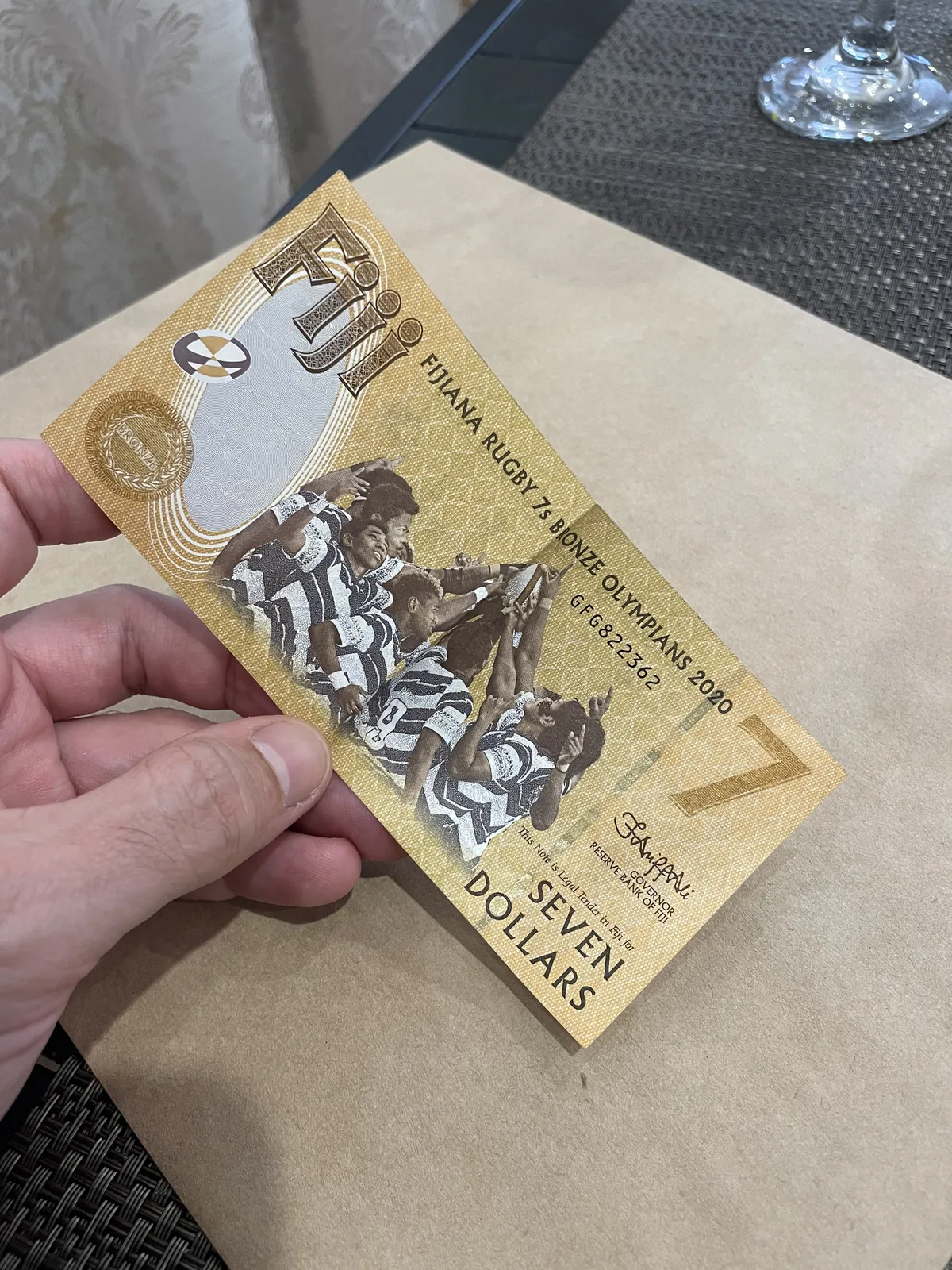A commemorative seven-dollar Fijian banknote held in one hand